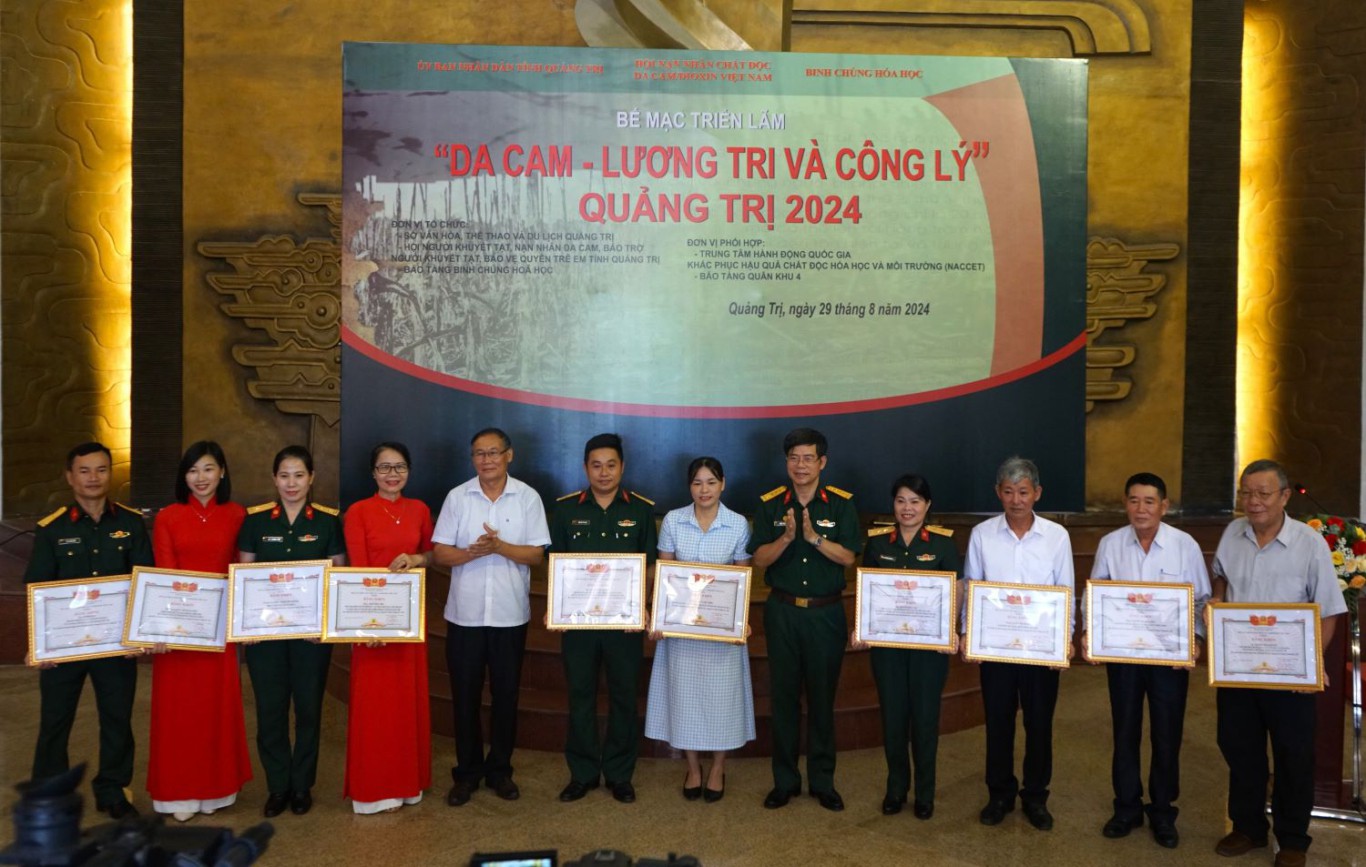 Đại t&aacute;, TS Phạm Xu&acirc;n Hưng, Ph&oacute; Chủ tịch Hội Nạn nh&acirc;n chất độc da cam/dioxin Việt Nam v&agrave; đồng ch&iacute; Nguyễn Huy H&ugrave;ng, Ph&oacute; Gi&aacute;m đốc Sở Văn h&oacute;a Thể thao v&agrave; Du lịch tặng hoa v&agrave; bằng khen cho c&aacute;c c&aacute; nh&acirc;n c&oacute; nhiều đ&oacute;ng g&oacute;p cho sự th&agrave;nh c&ocirc;ng của Triển l&atilde;m -Ảnh: L.T